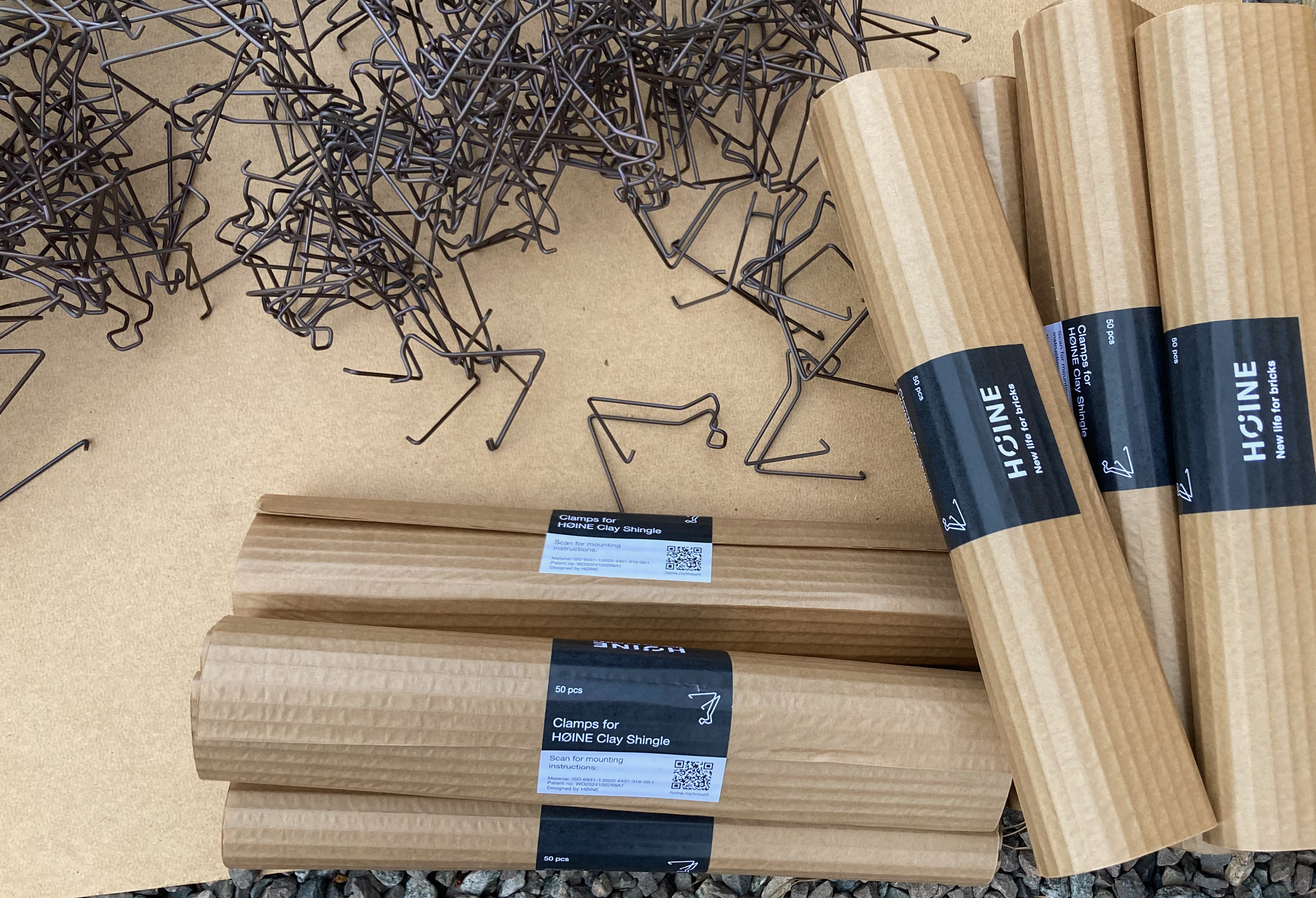 Packaged HØINE clay shingle clamps displayed beside loose metal clamps.