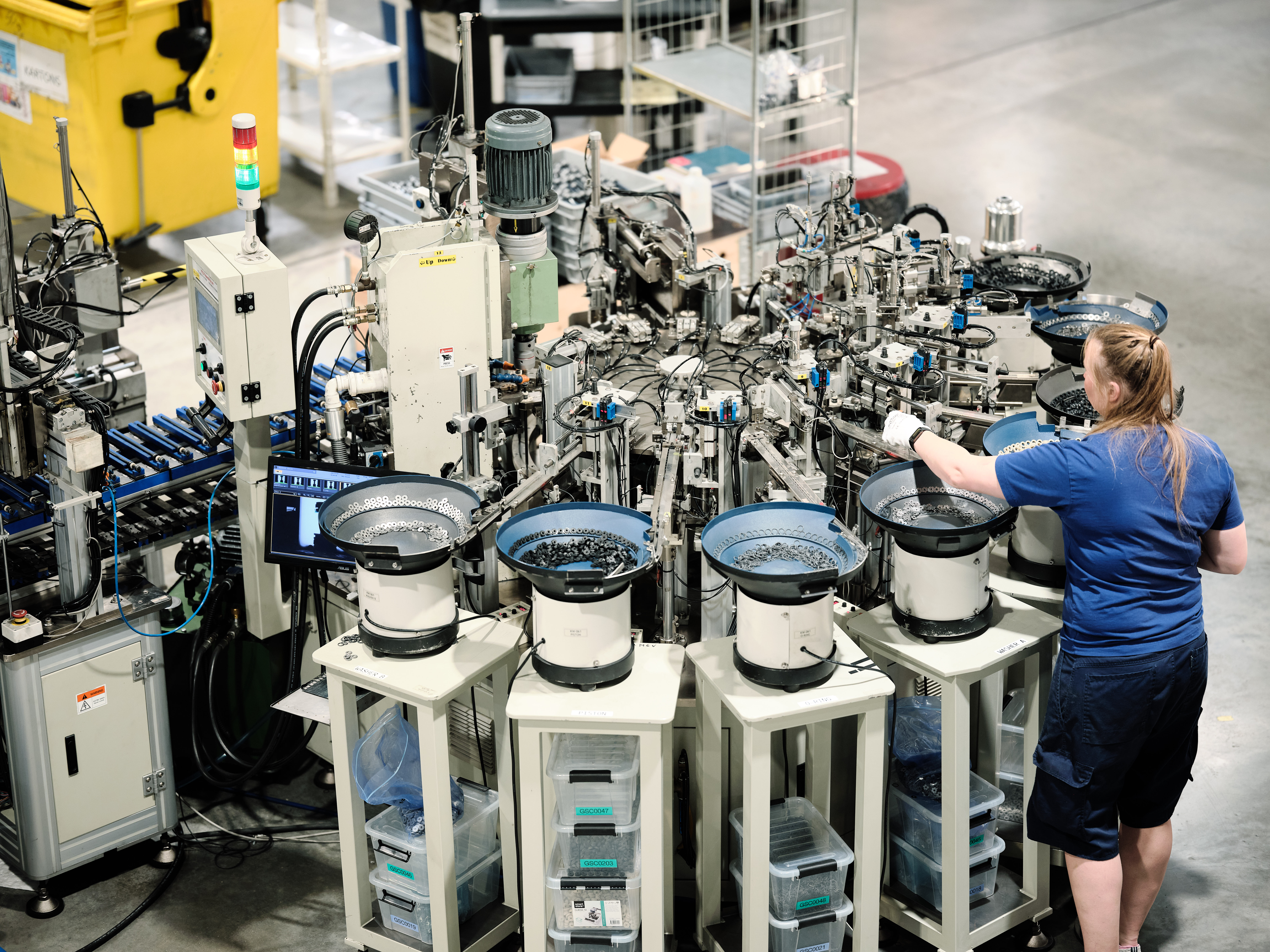Worker operating an automated manufacturing machine with multiple feeders.