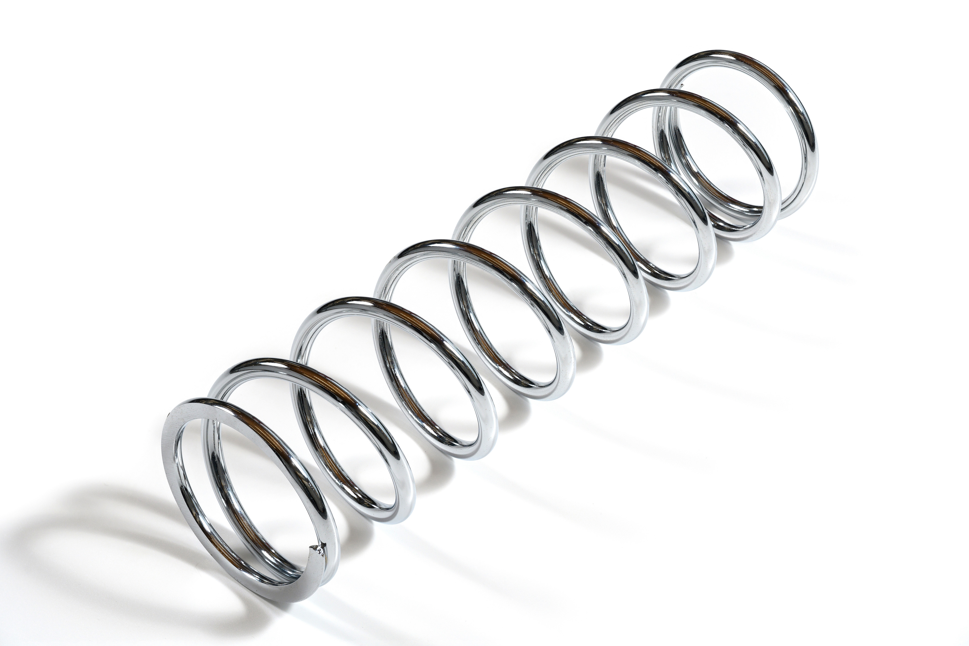 Chrome compression spring on a white background.