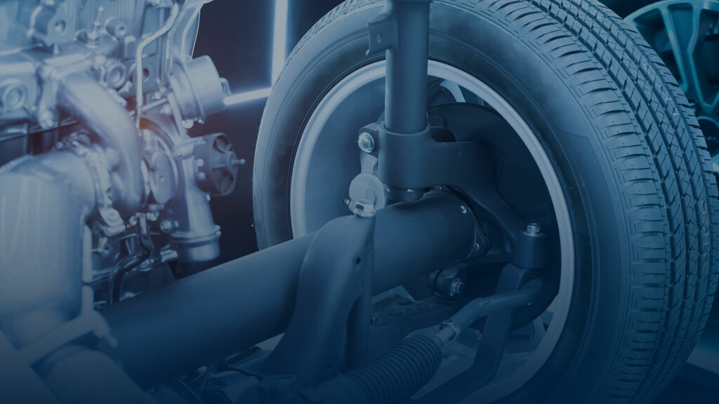 Close-up of a vehicle’s suspension system, showcasing a wheel and surrounding mechanical parts. The lighting enhances the shiny, metallic textures.