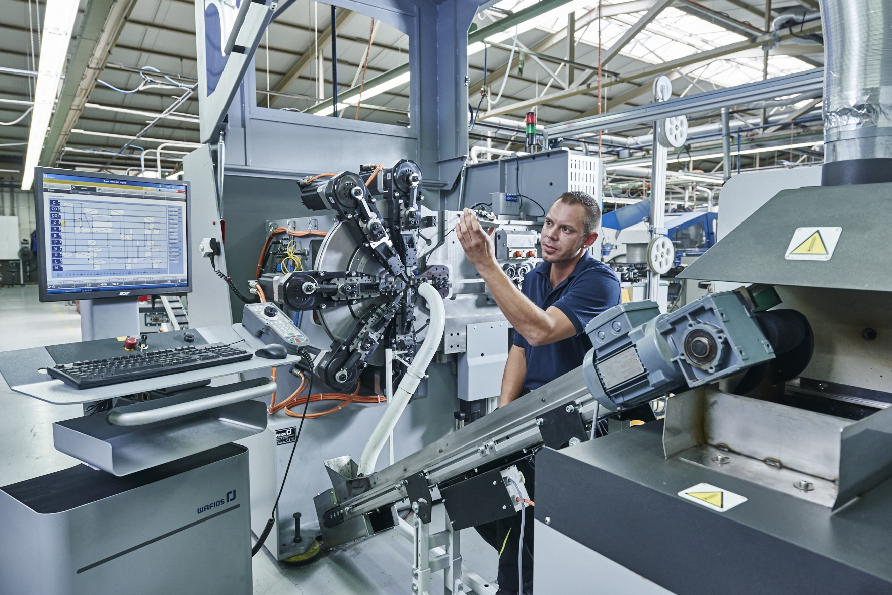 A man in a workshop focuses on assembling a bicycle. Tools and parts surround him, highlighting a busy, industrious atmosphere.