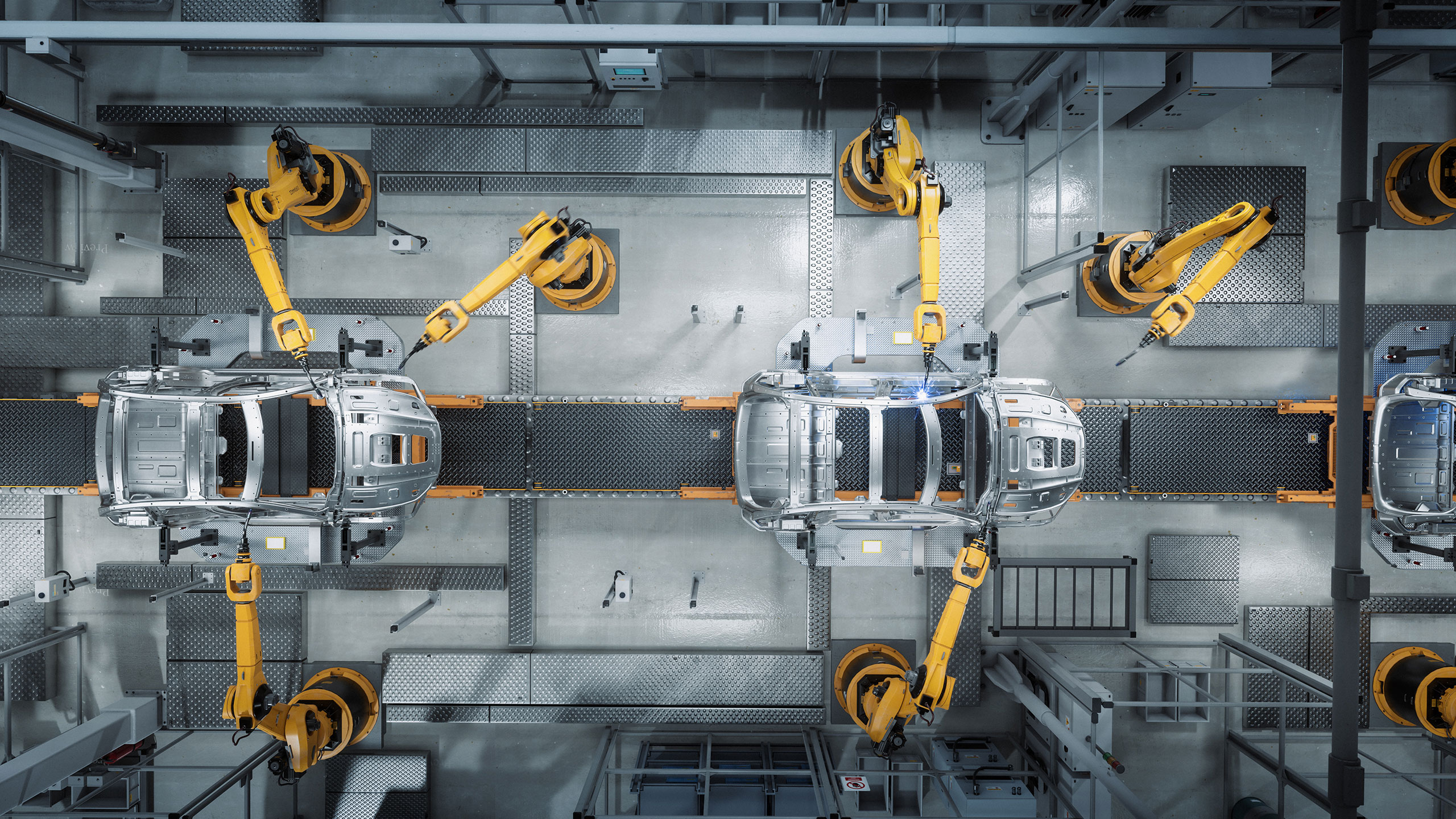 Overhead view of robotic arms assembling car bodies on an automotive assembly line.