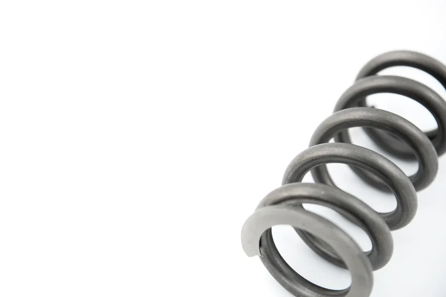 Close-up of a steel coil spring on a white background.
