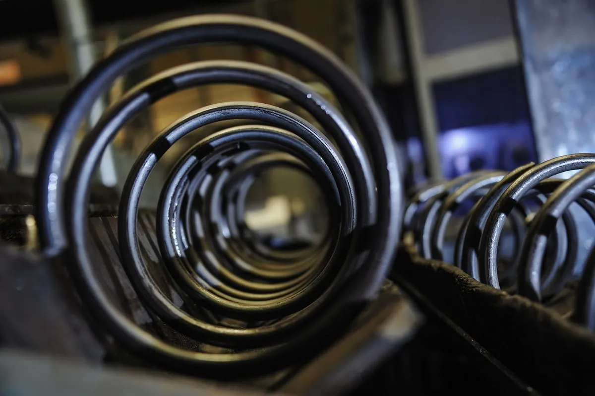 A side angle view of a black compression spring for suspension systems