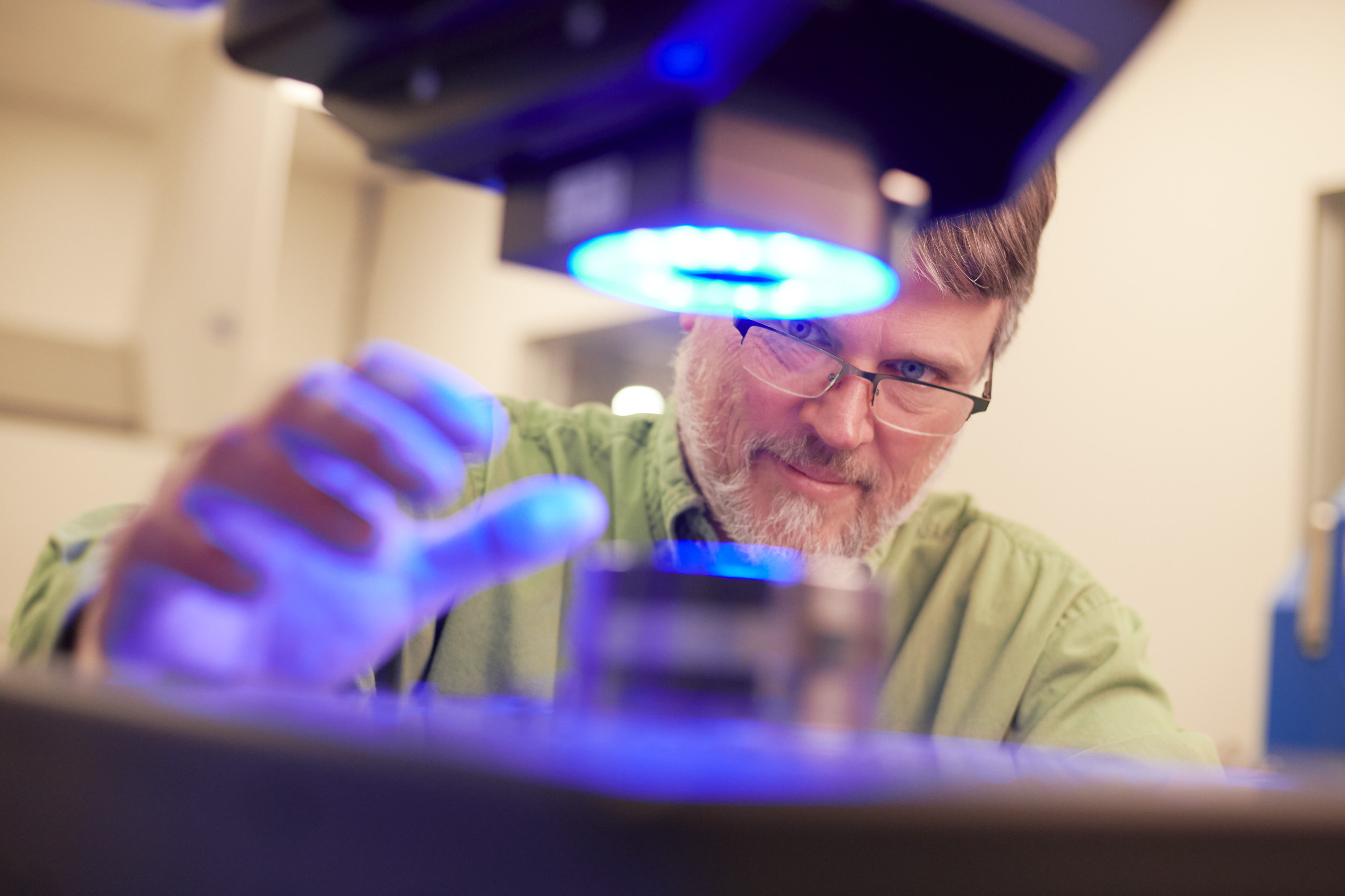 Technician inspecting a metal component under a blue light.