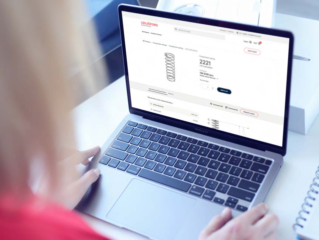 A person in a red shirt uses a laptop displaying an e-commerce website with product details.