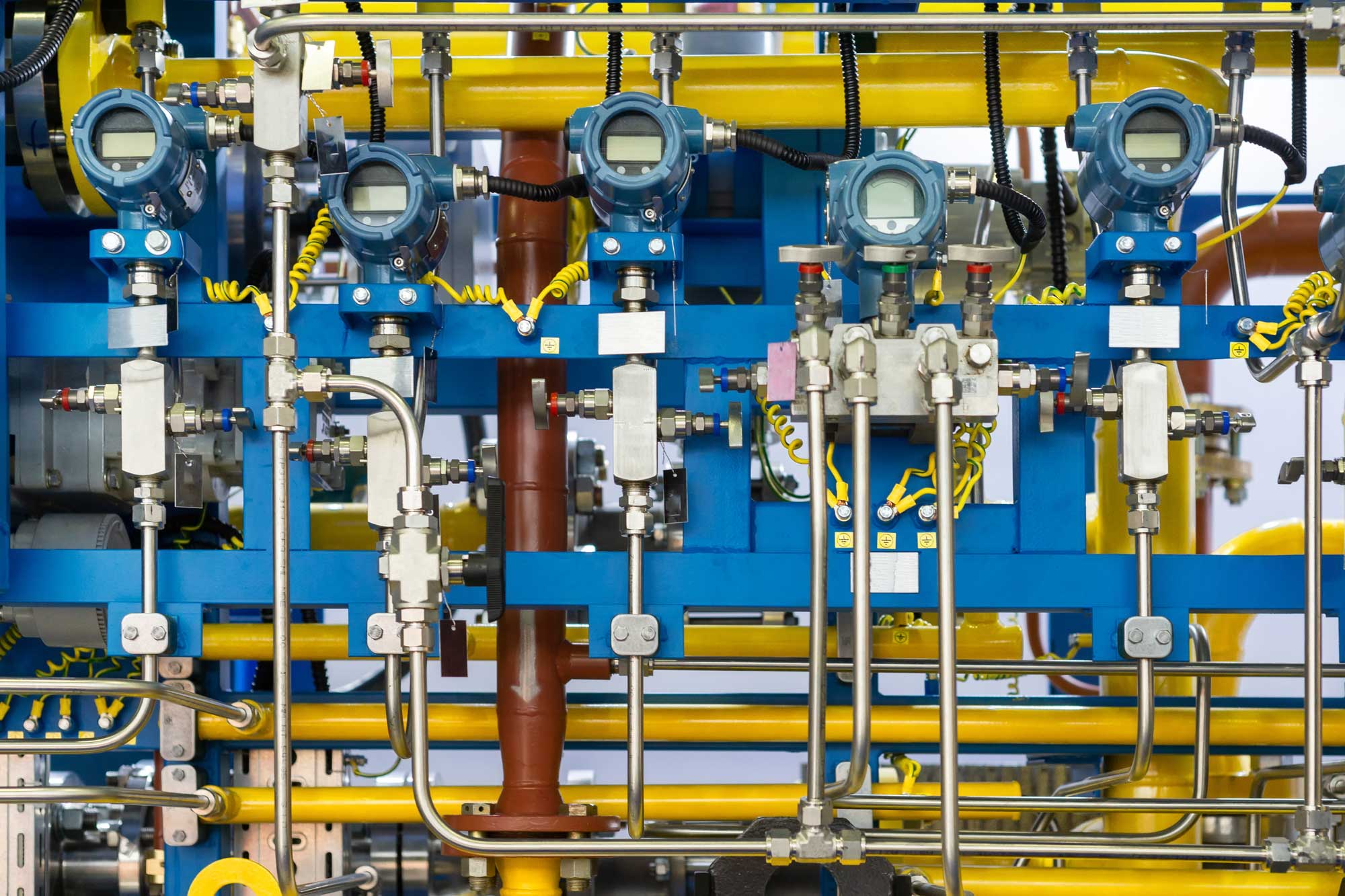 A complex array of industrial pipes and gauges in vibrant blue and yellow.
