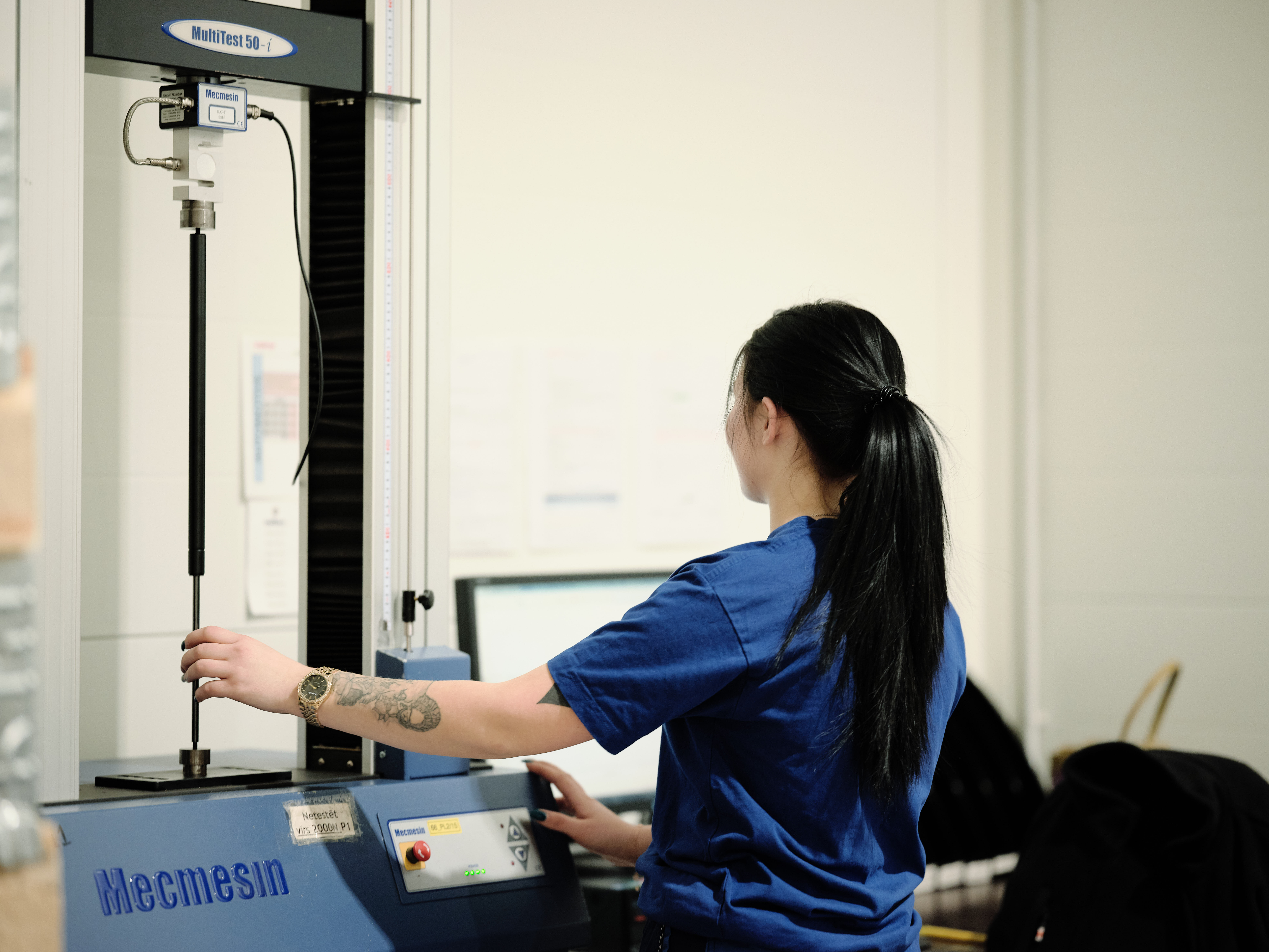 A woman in a blue shirt is producing a custom-made compression gas spring.