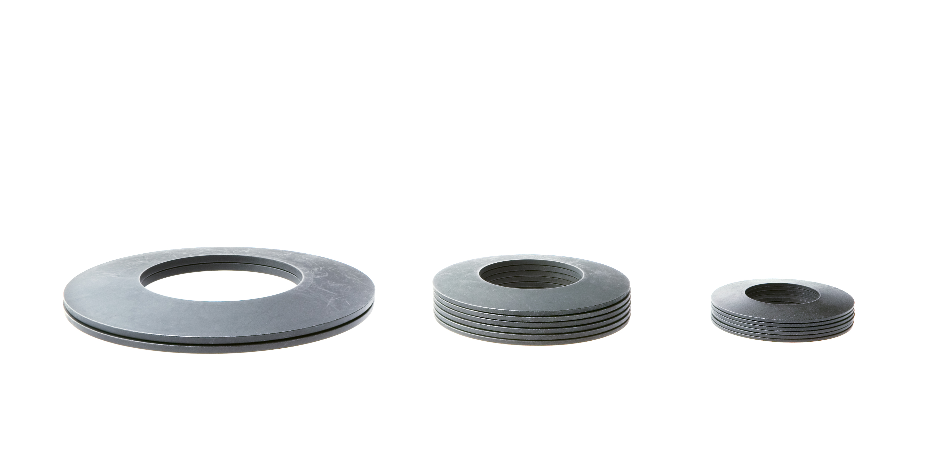Three stacks of metal disc springs of varying heights and sizes on a white background.