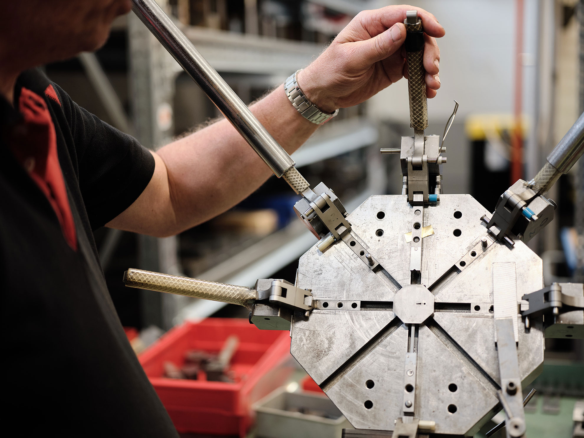 A factory worker adjusting a metal forming jig.