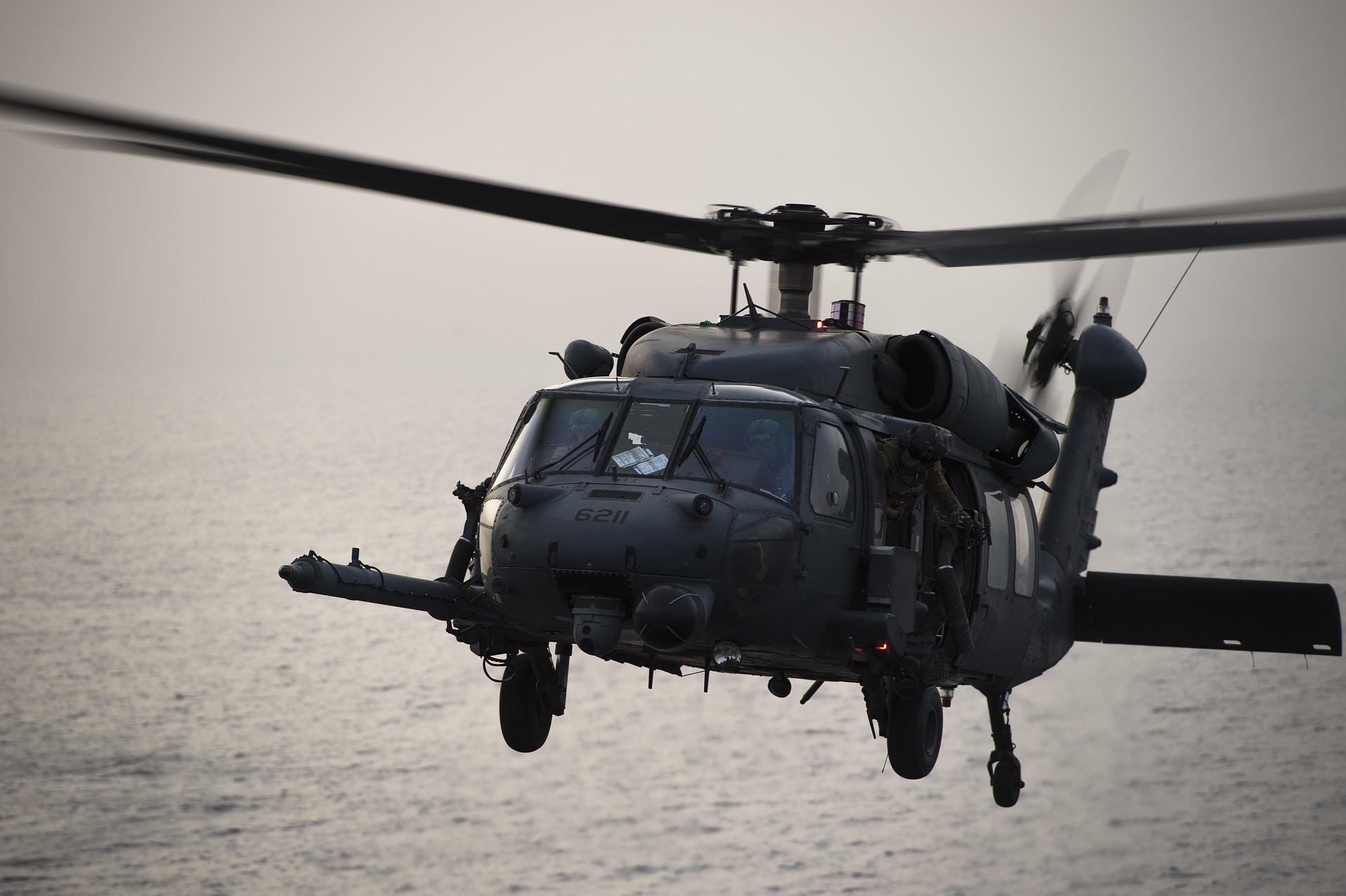 Military helicopter flying low over the ocean.