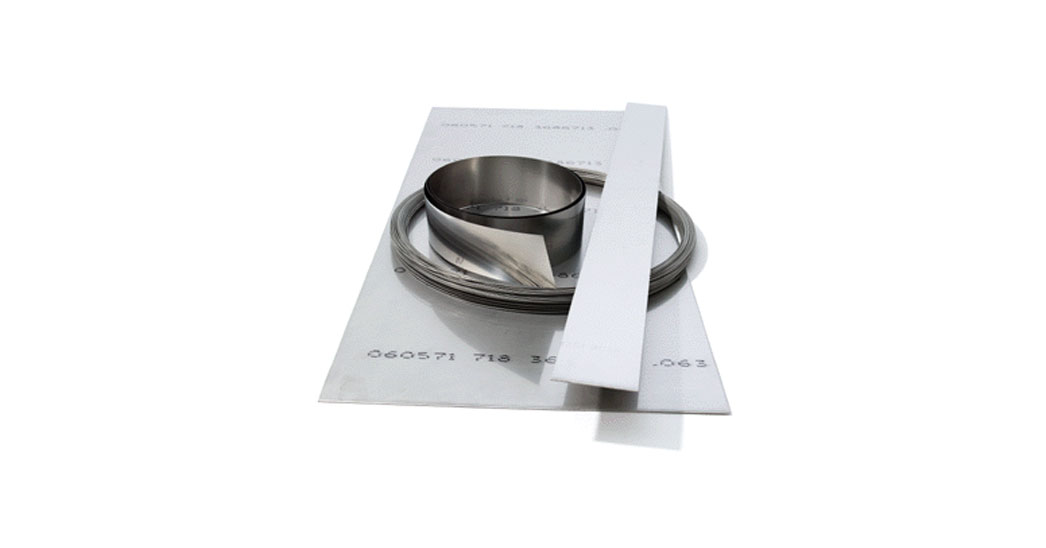 Four different material samples, including a coiled metal strip, on a white surface.